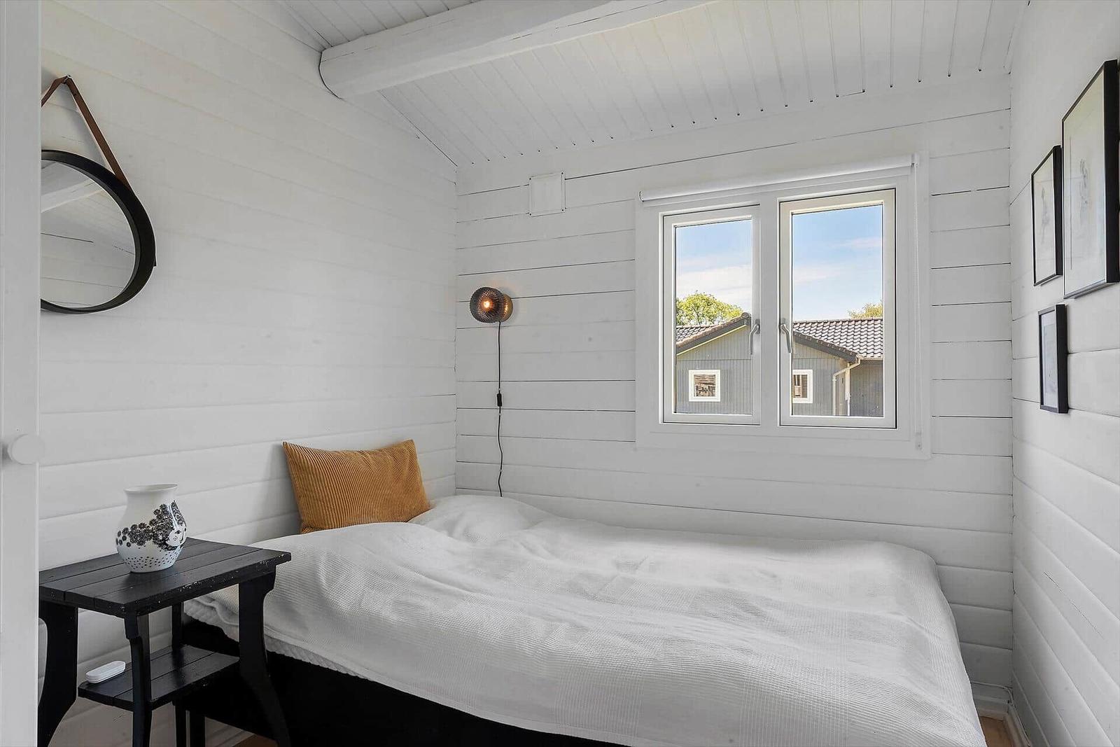 Bedroom with white bed, window, and wall decor.