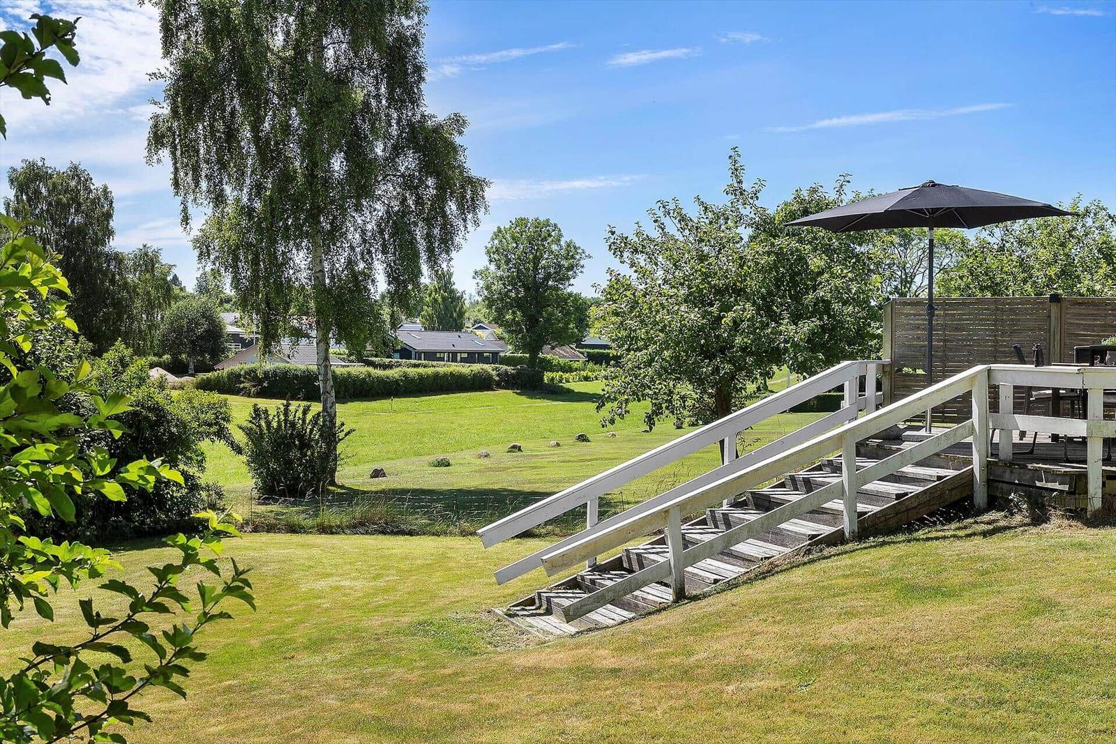 Deck with umbrella and stairs to a green lawn.