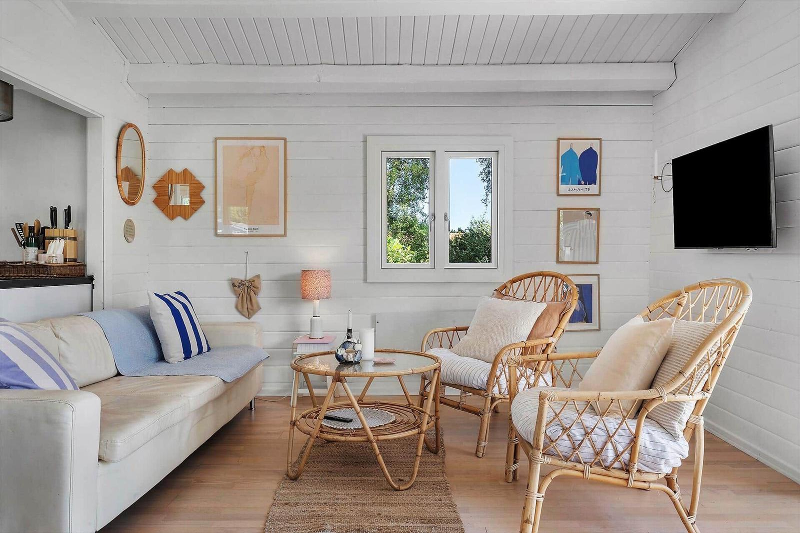 Living room with sofa, rattan chairs, and TV mounted on the wall.