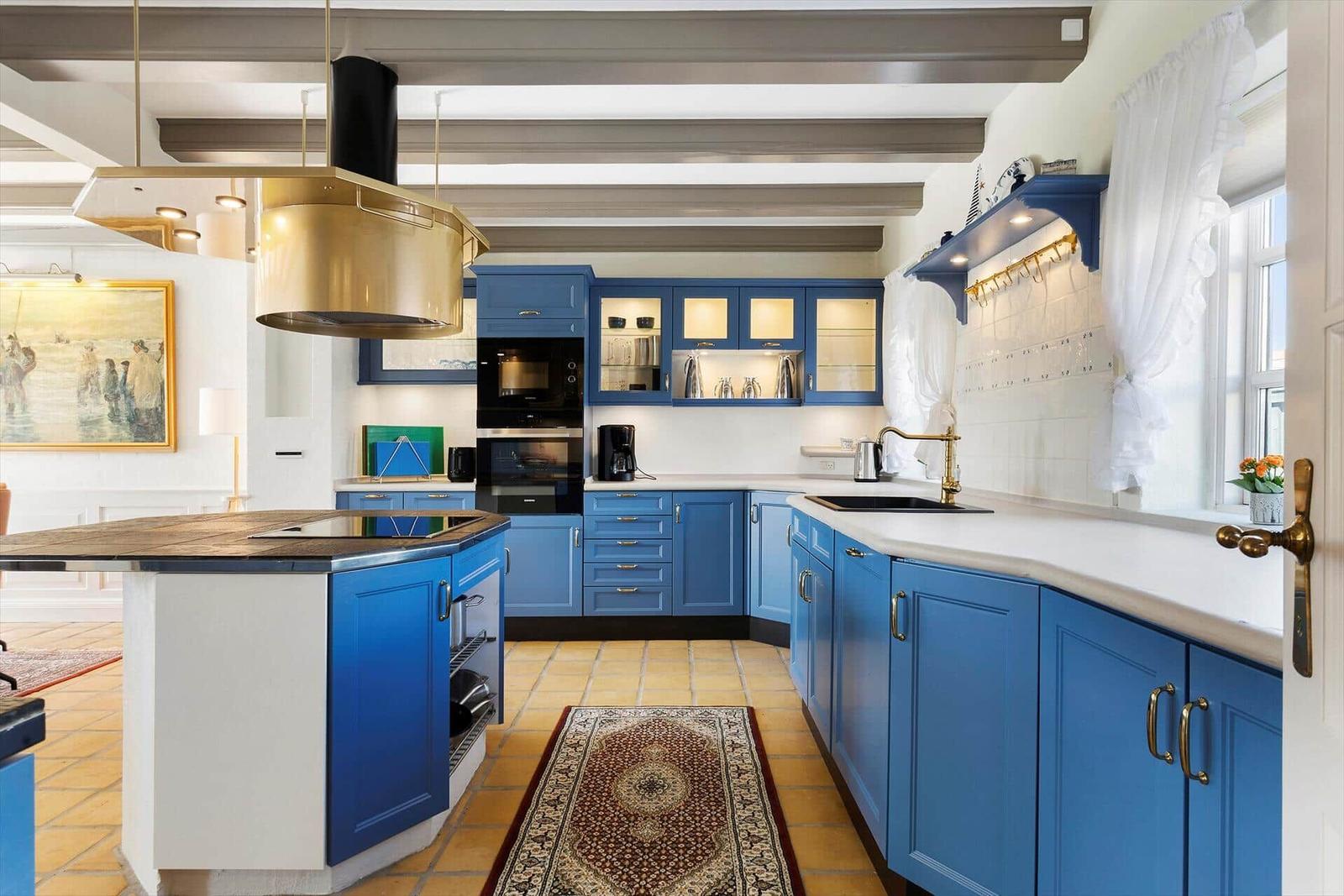 Kitchen with blue cabinets, white countertops, and gold fixtures.
