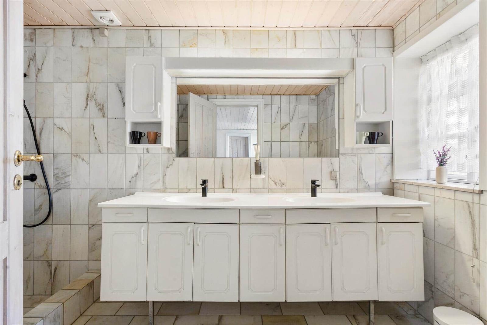 Bathroom with double sink, mirror cabinet, and window