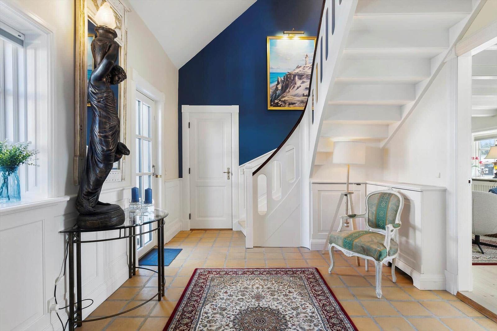 Entrance with staircase, statue, rug, and chair.