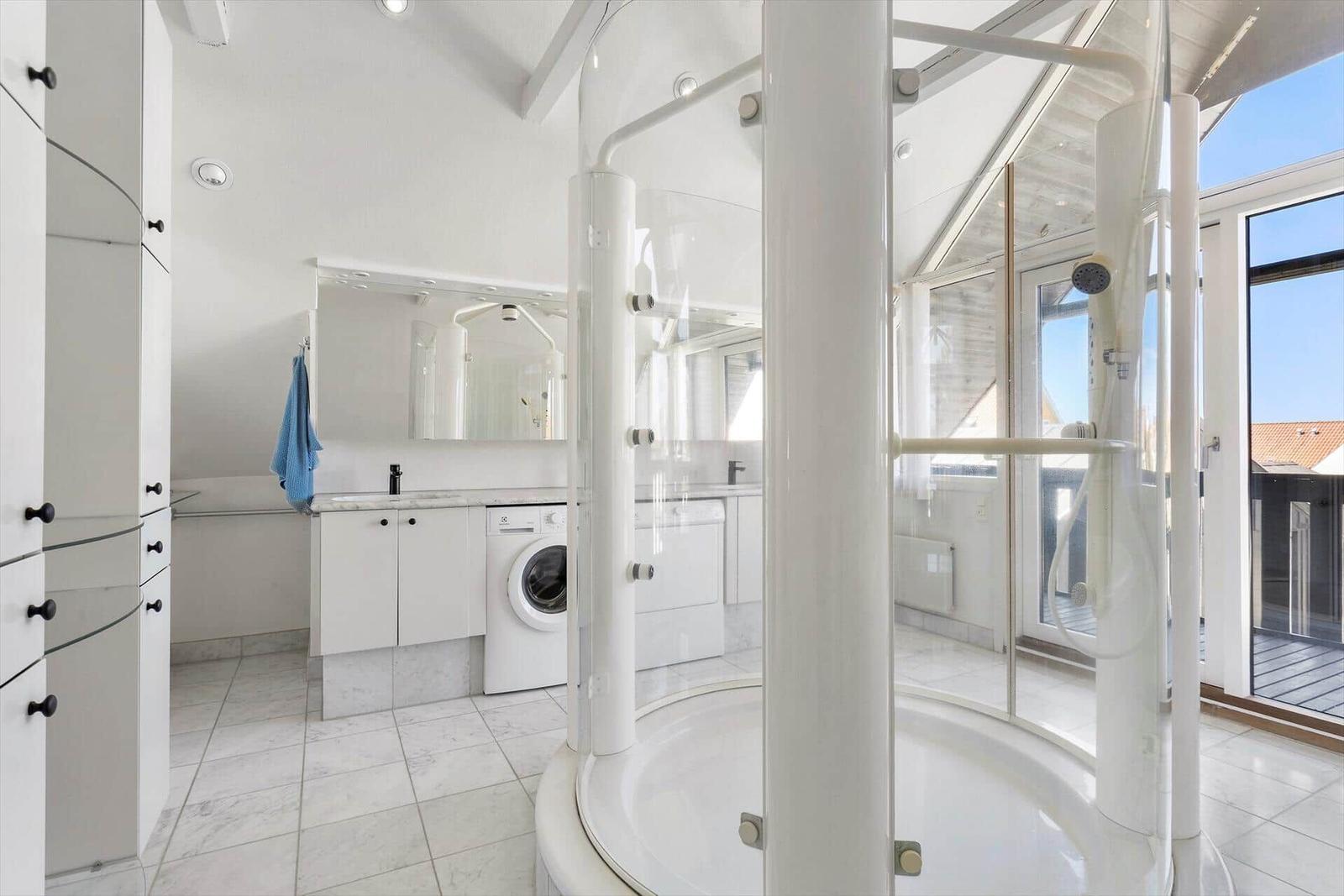 Shower area with glass surround and washing machine in bathroom