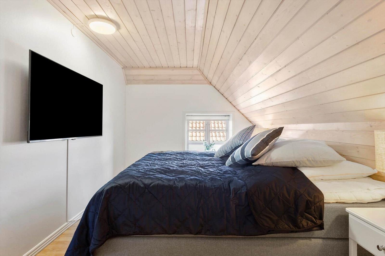 Bedroom with bed, TV, and wooden ceiling
