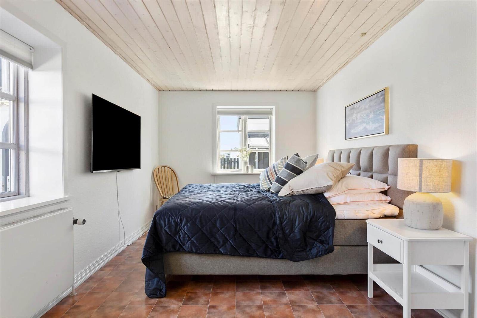 Bedroom with bed, TV, and windows.