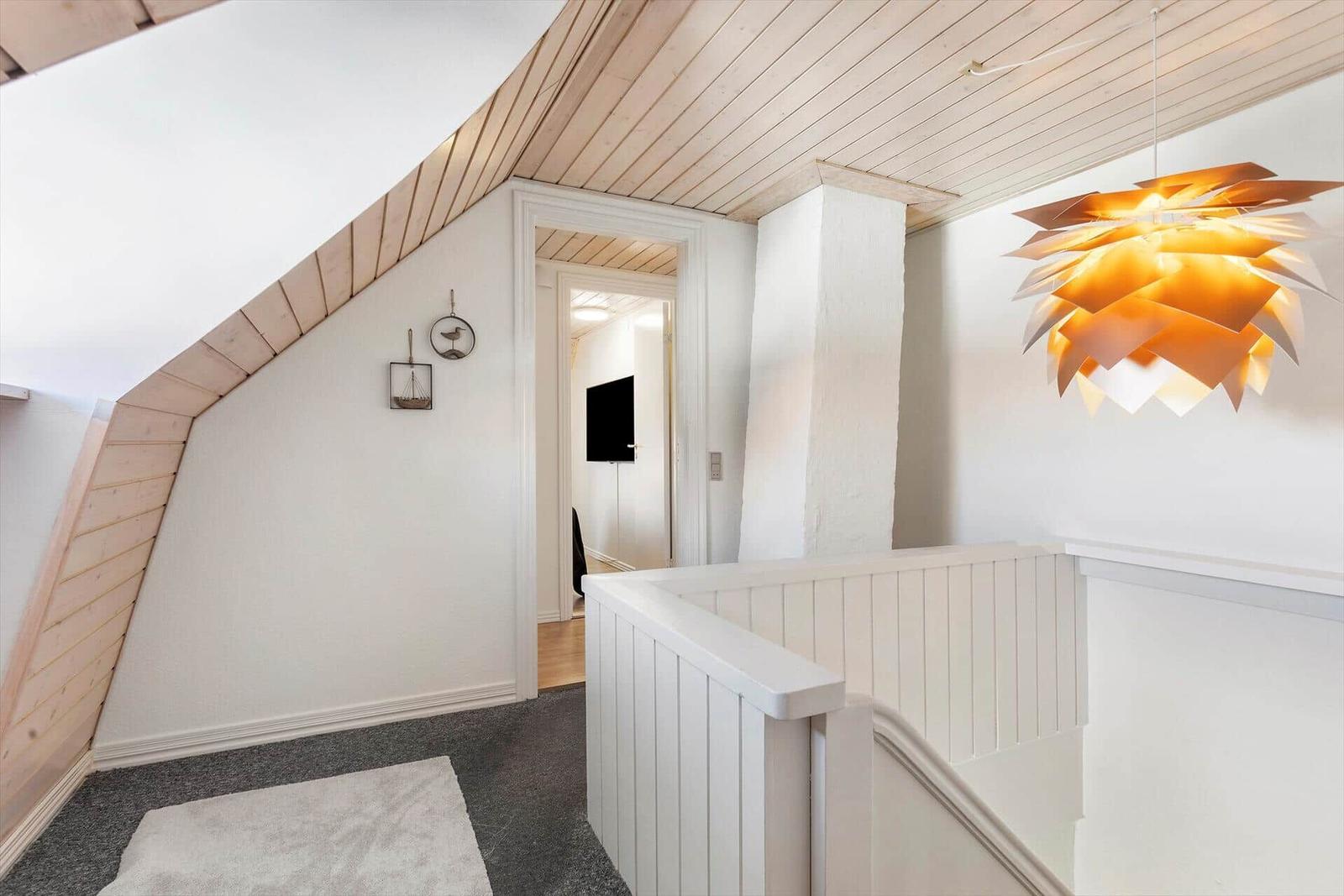 Entrance area with wooden ceiling, white stairs, and a hanging lamp.