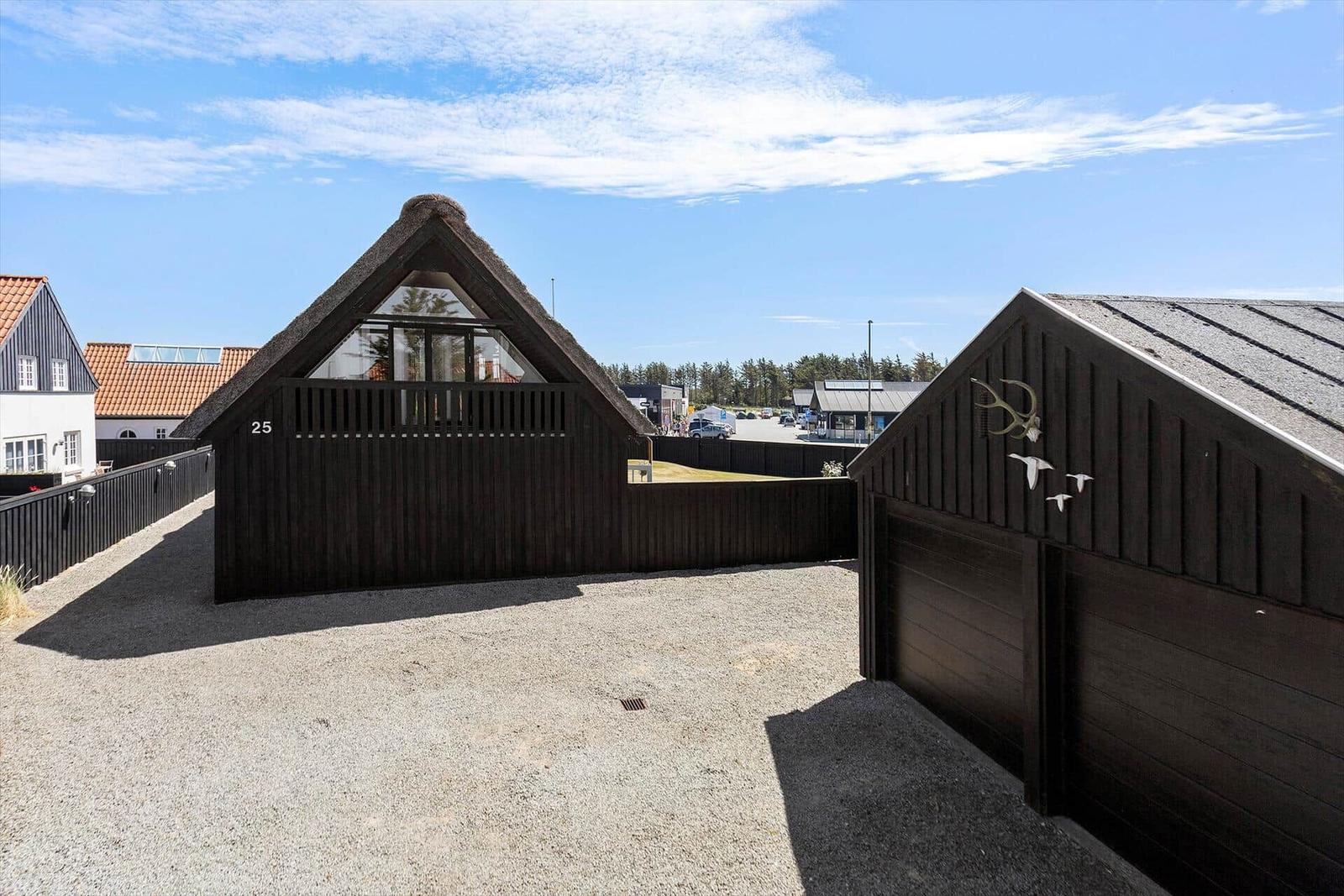 Wooden house with thatched roof and garage area. Number 25. View of residential area.