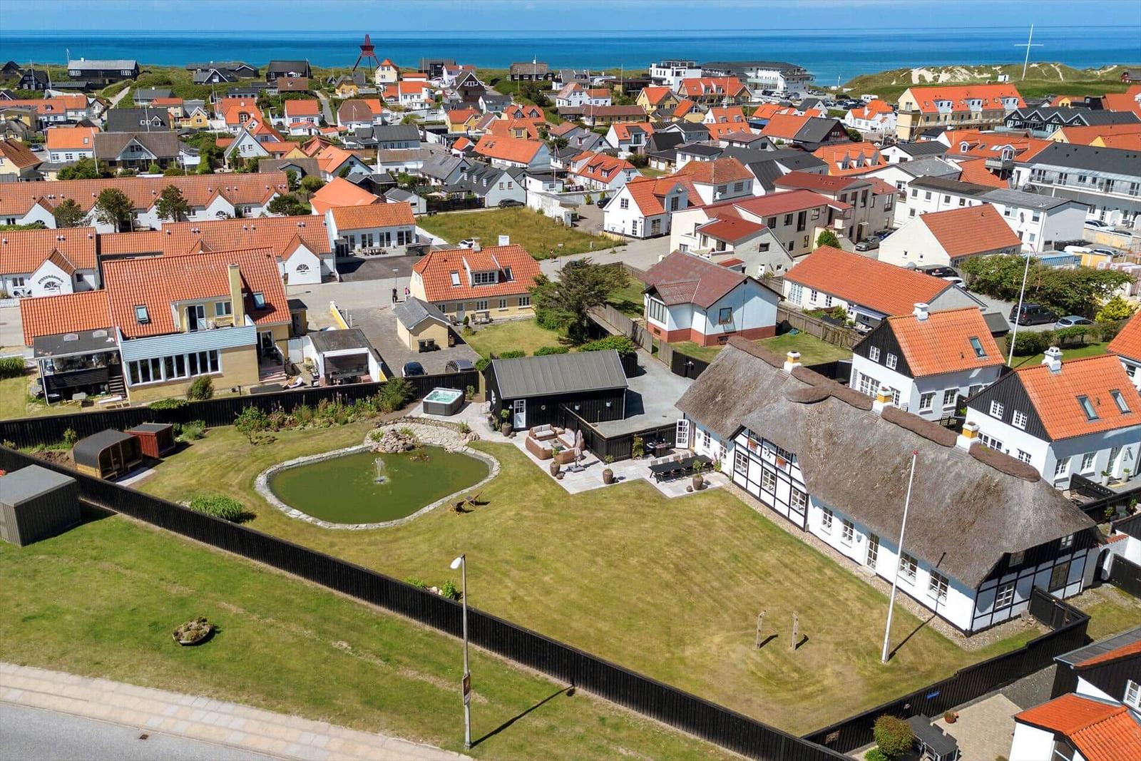 House with garden, pond, and view of sea and village.