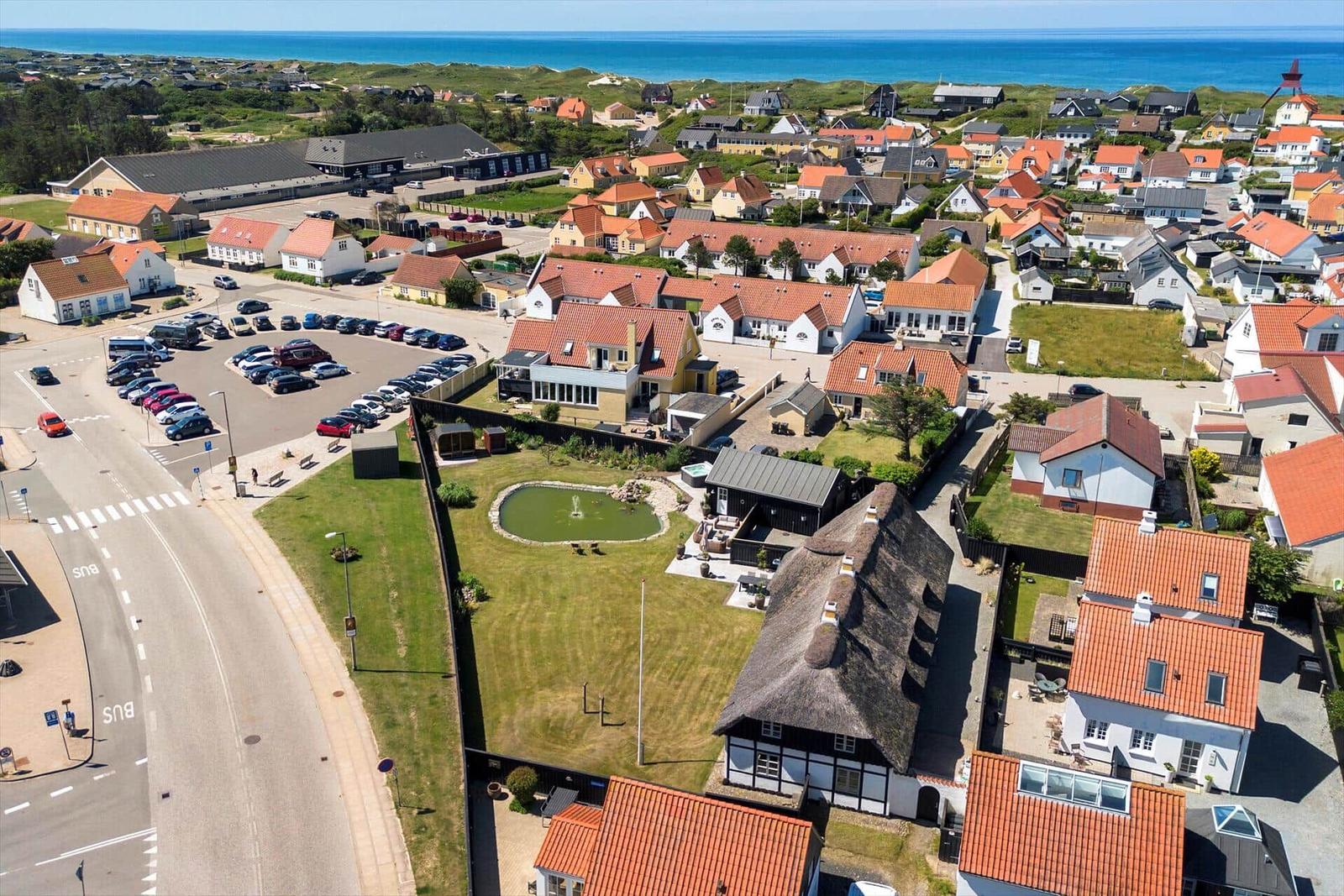Aerial view of coastal village with houses, parking, and sea view.