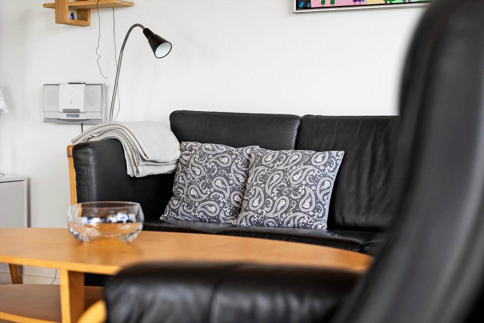 Schwarzes Ledersofa mit Kissen und Tisch im Wohnzimmer.