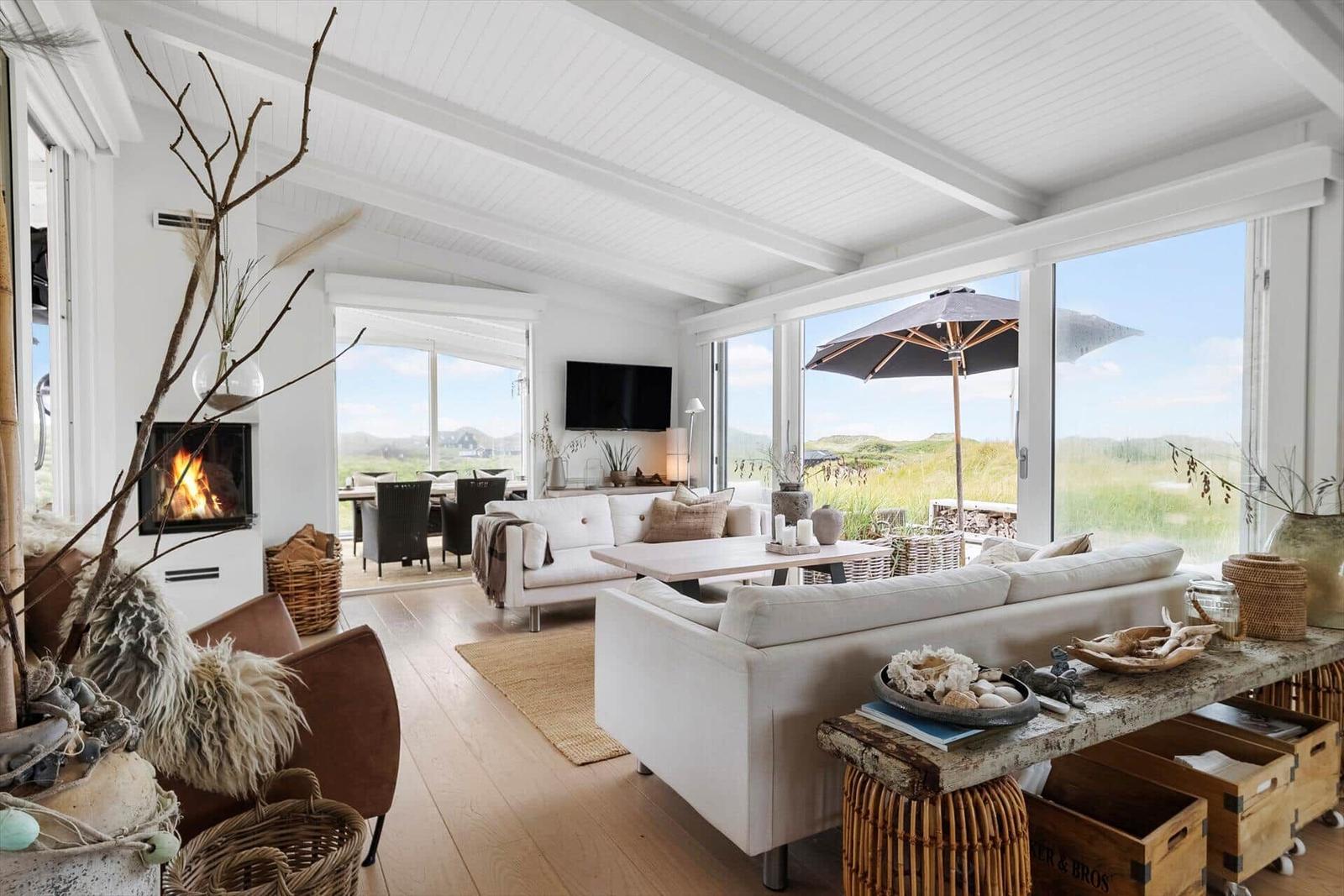 Living area with fireplace, sofa, and view of terrace with umbrella.