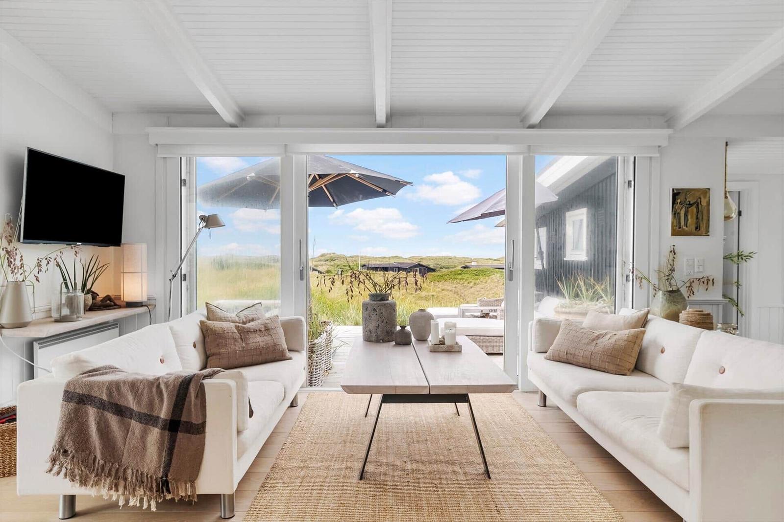 Living room with two sofas, coffee table, and view of terrace with umbrellas.