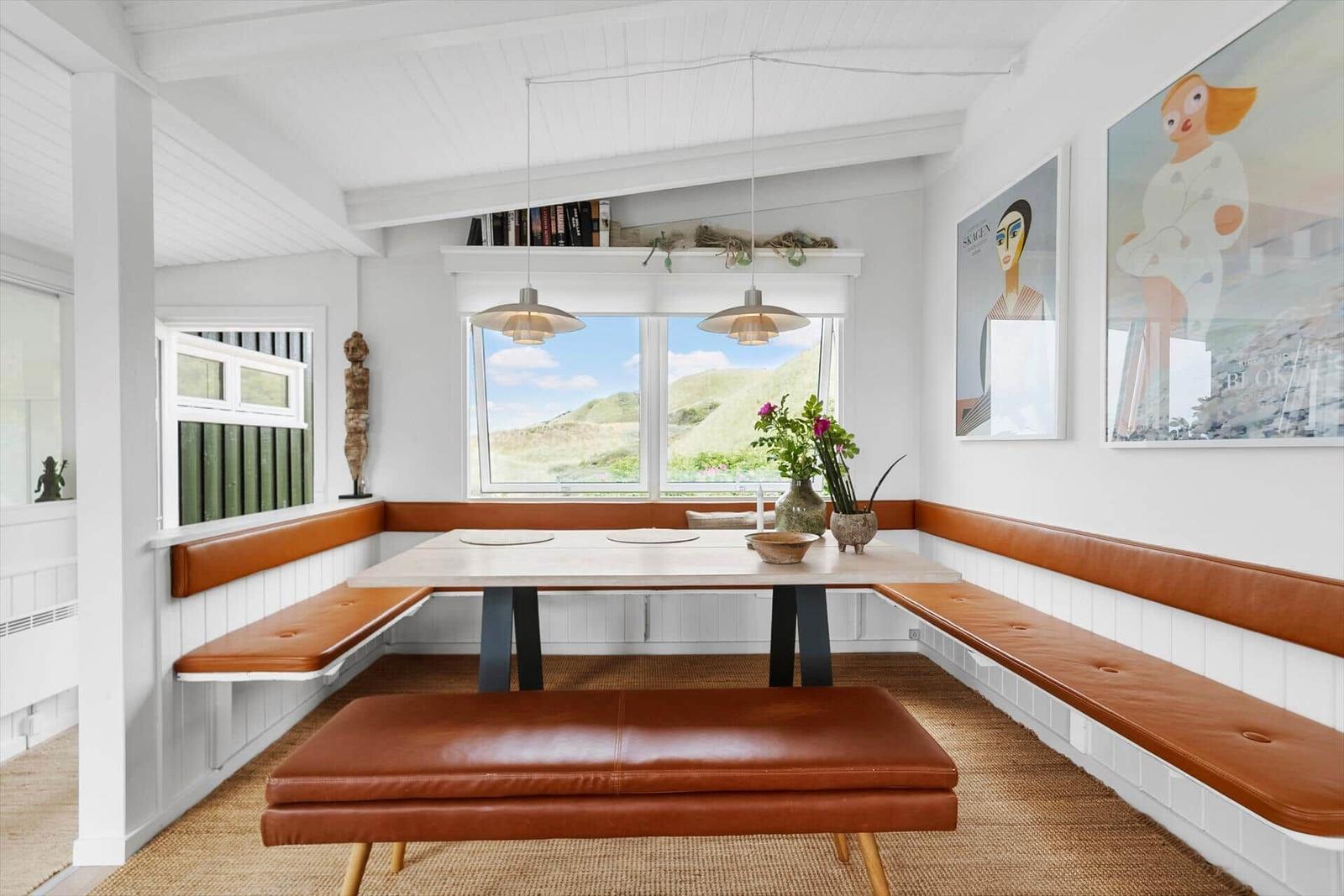 Dining room with brown leather seating and view of green hills.