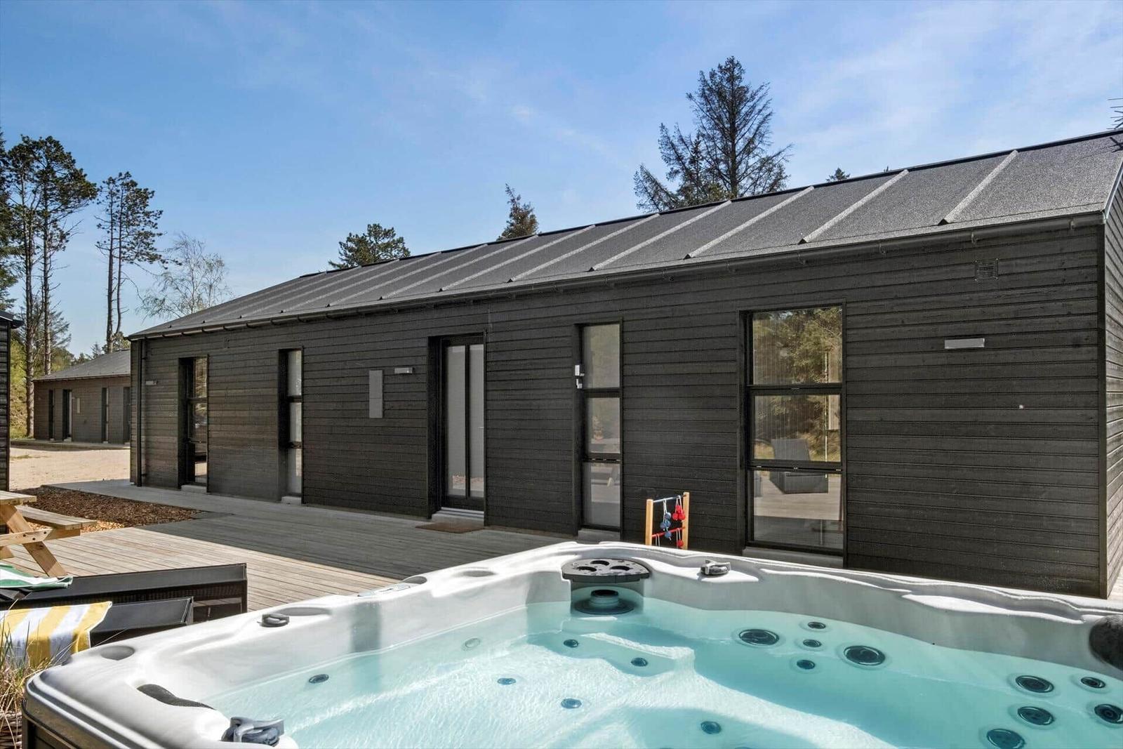 Moderne Holzhütte mit Whirlpool und Terrasse im Wald.