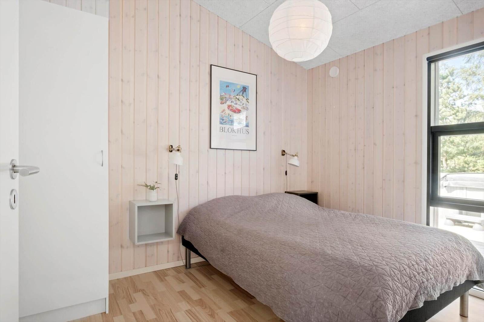 Schlafzimmer mit Bett, Wandbild und Fenster zum Balkon.