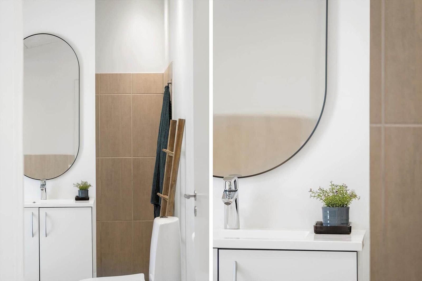 Badezimmer mit Spiegel, Waschbecken und Pflanze.