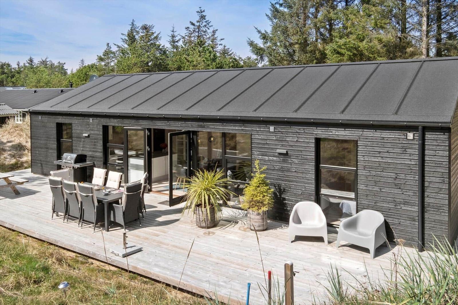 Moderne Villa mit Terrasse, Grill und Sitzgelegenheiten im Freien.