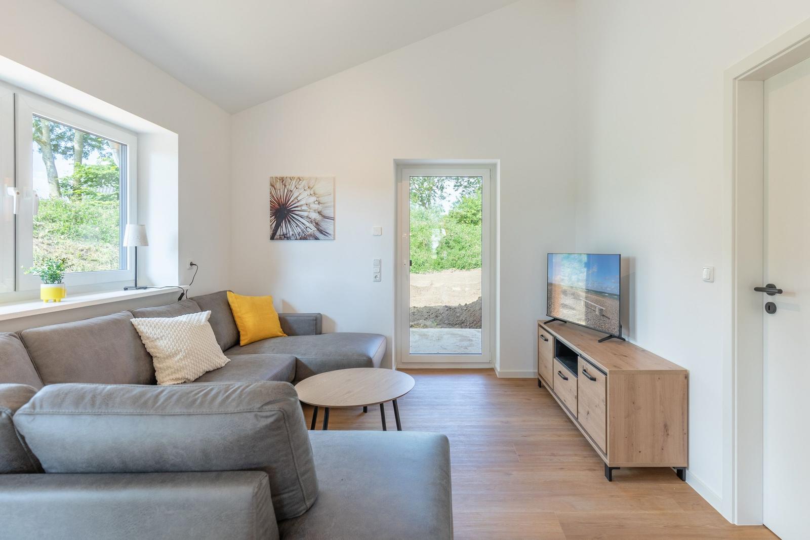 Wohnzimmer mit Sofa, TV und Fenster zur Außenseite.