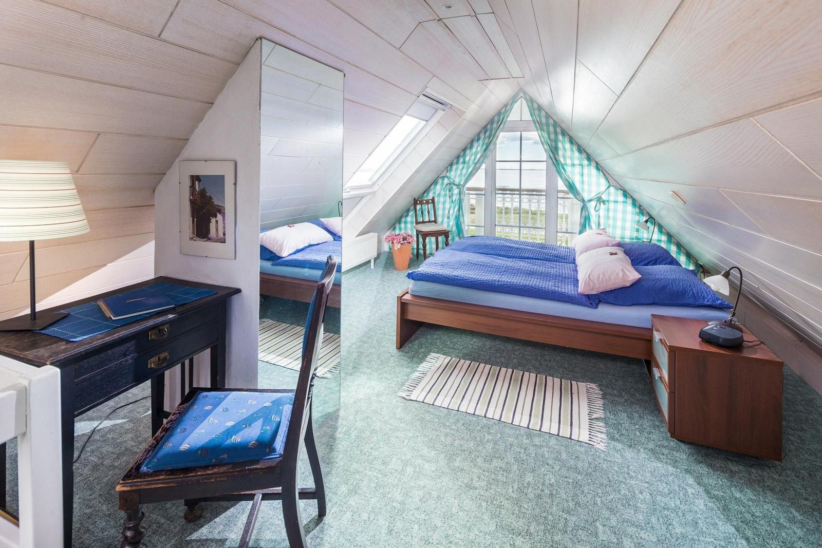 Dachgeschosszimmer mit Bett, Schreibtisch und Fenster mit Blick.