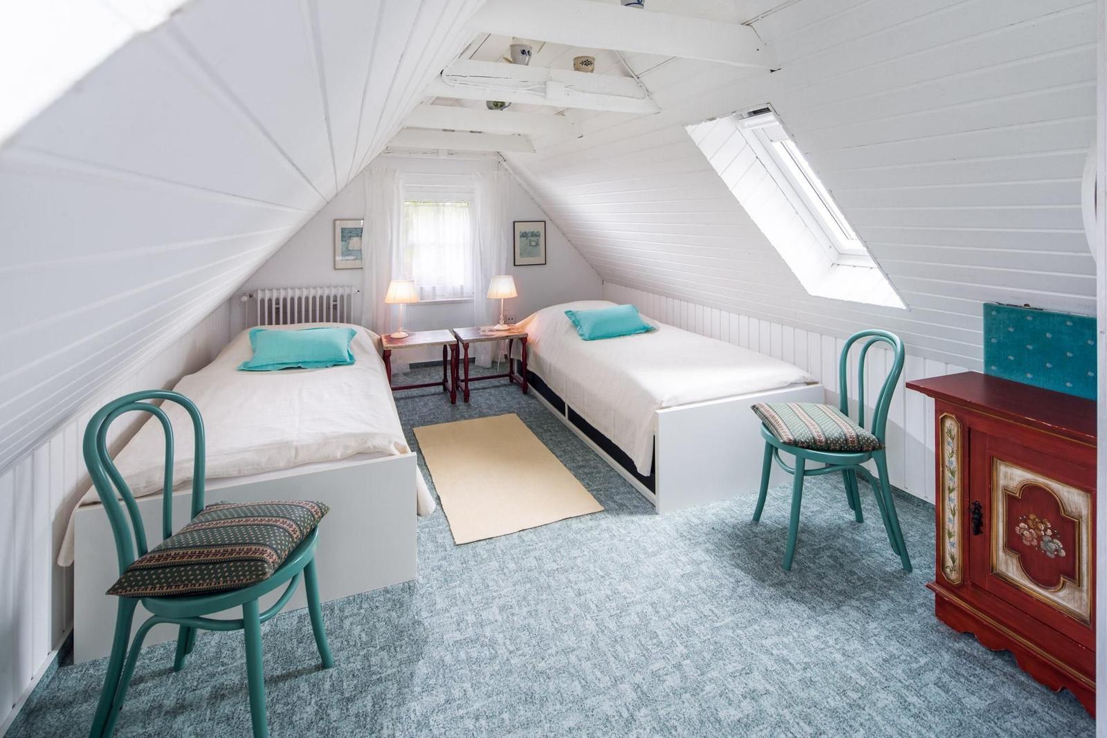 Zimmer mit zwei Betten, Schrank und Fenster unter Dach