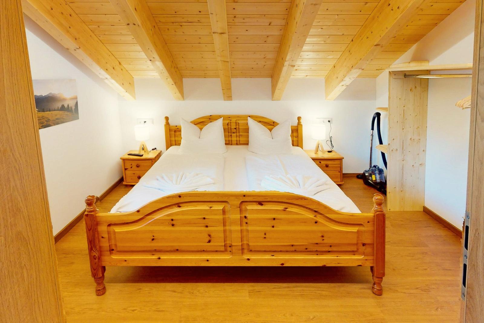 Schlafzimmer mit Holzbett, Nachttischen und Dachschrägen.