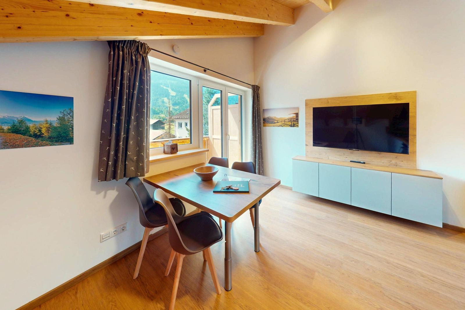 Essbereich mit Tisch, Stühlen und TV. Fenster mit Blick auf die Berge.