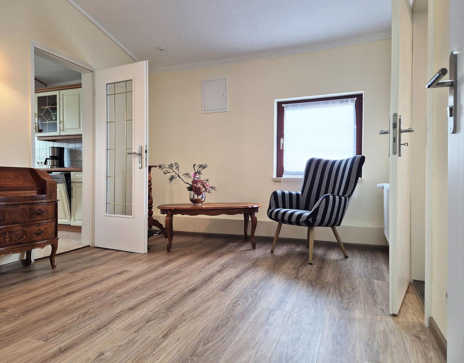 Living room with chair, table, and view into the kitchen.