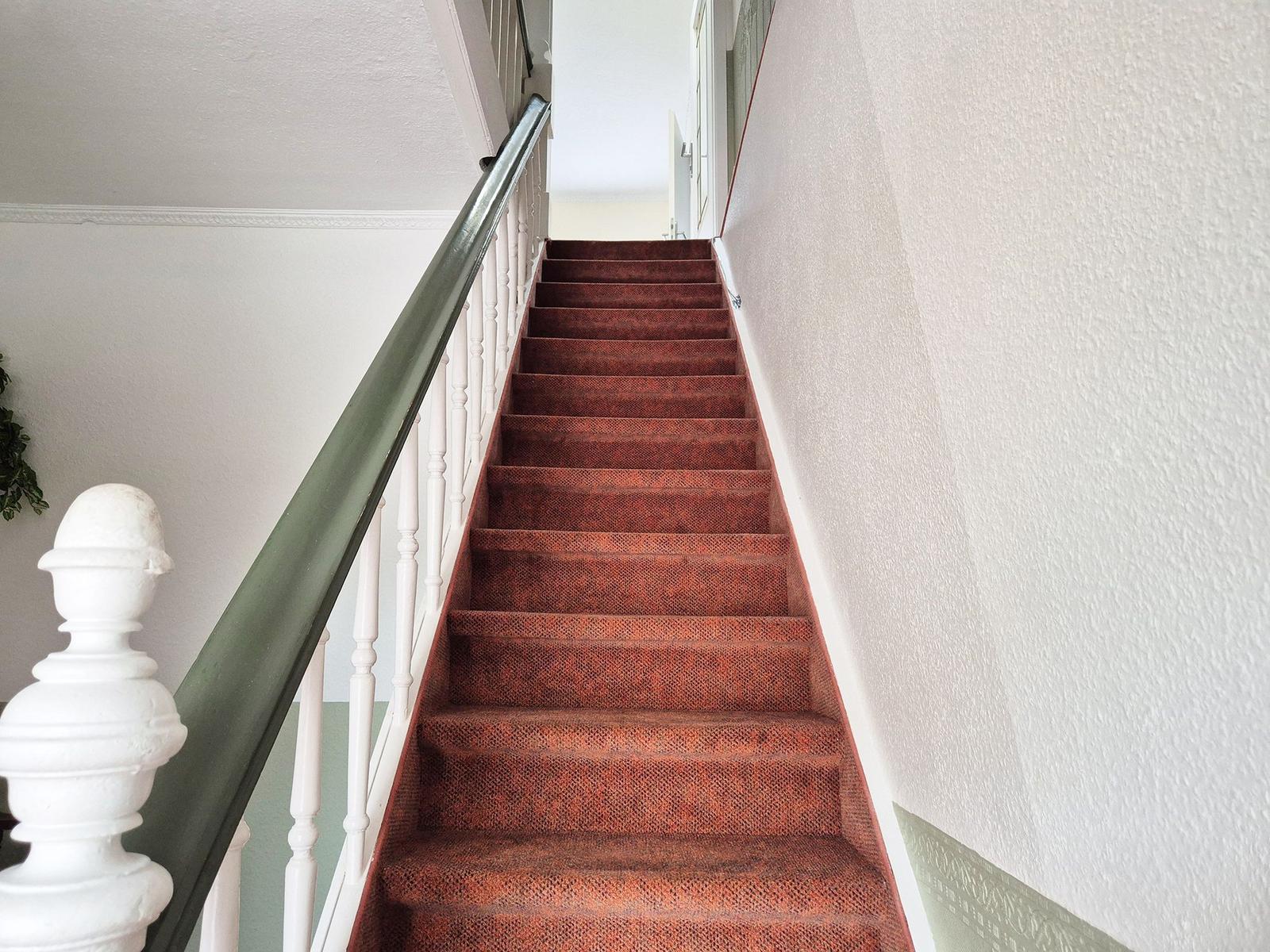 Staircase with red carpet and white balustrade leads upward.