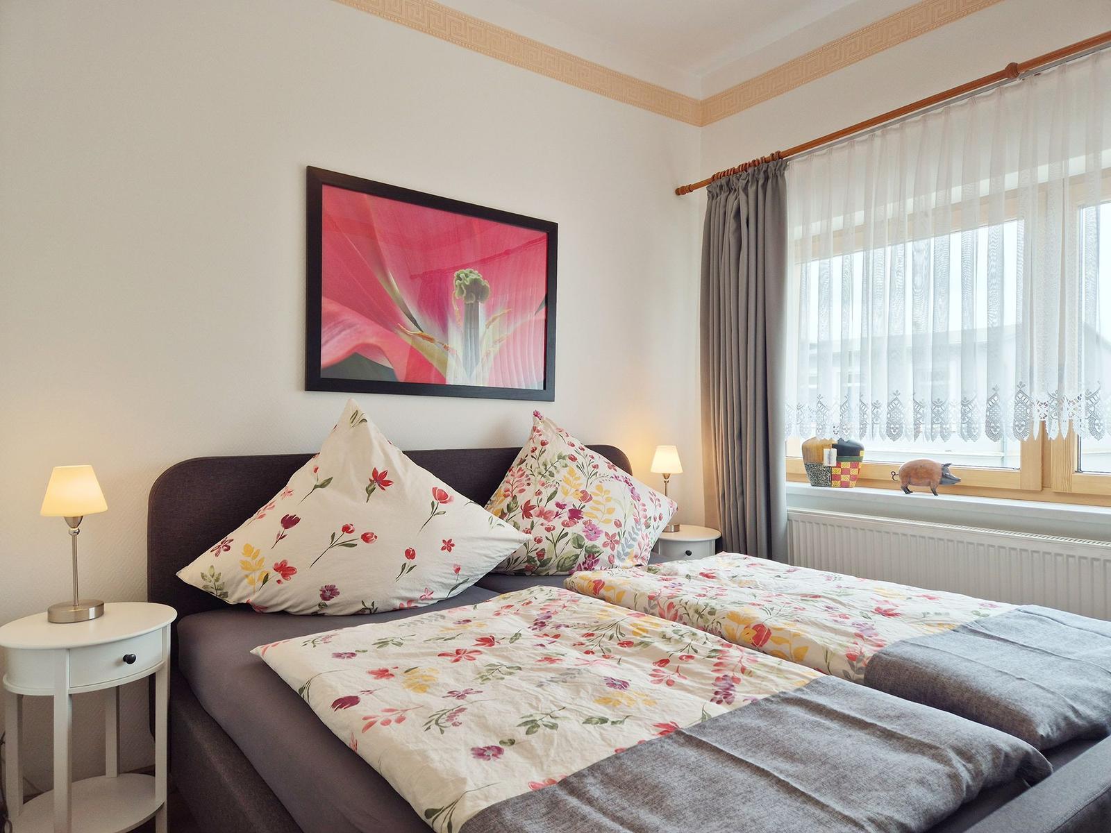 Bedroom with double bed, two nightstands, and window with curtains.