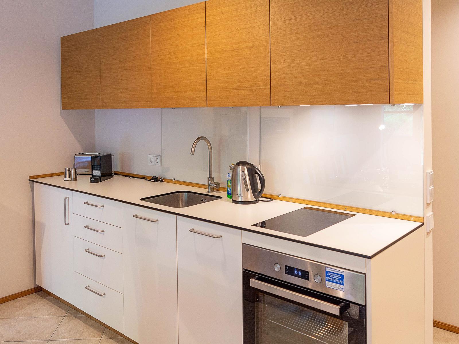 Küche mit Holzschränken, Edelstahlspüle und Kochfeld