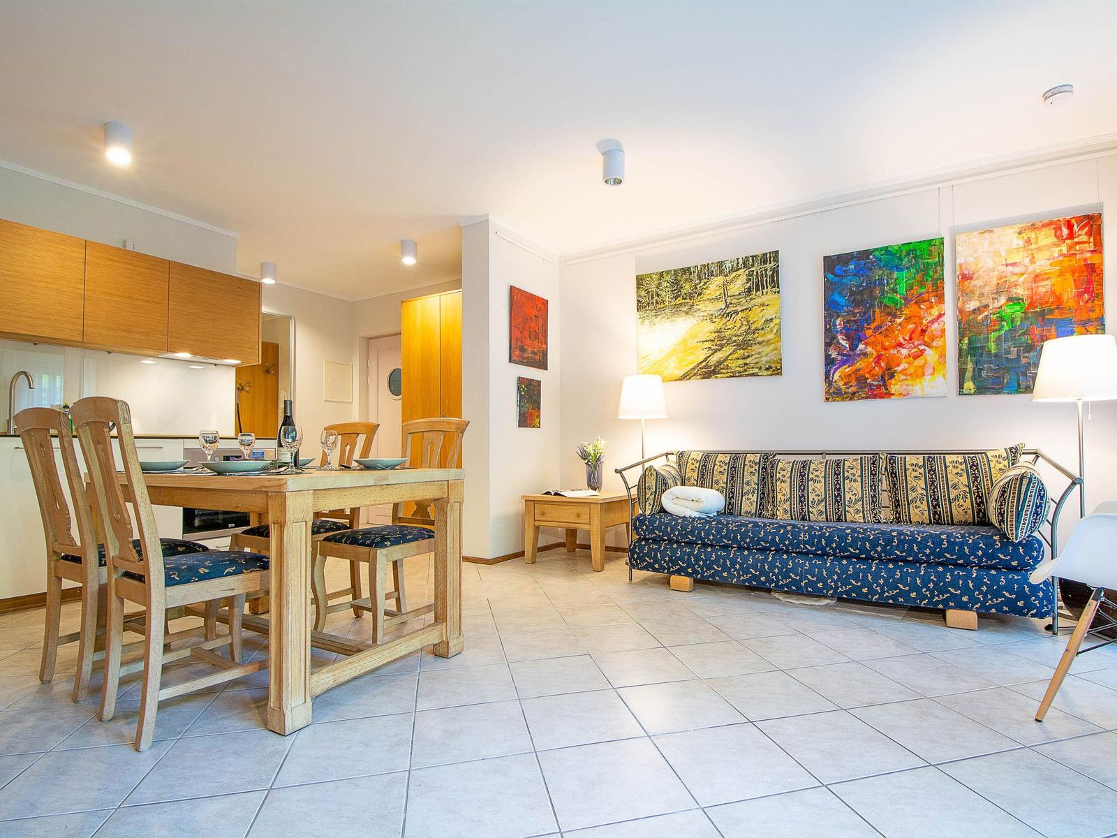 Wohn- und Essbereich mit Sofa, Tisch und Wandbildern