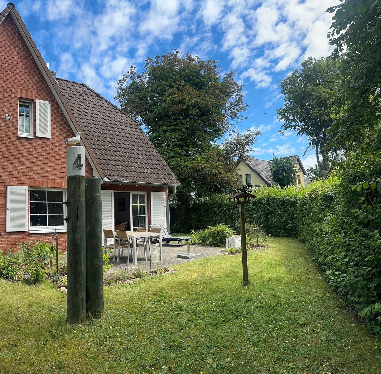 Rotes Backsteingebäude mit Terrasse und Garten unter blauem Himmel.