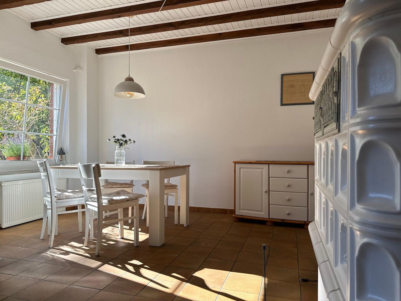 Esszimmer mit Tisch, Stühlen und Fenster. Holzbalken an der Decke.