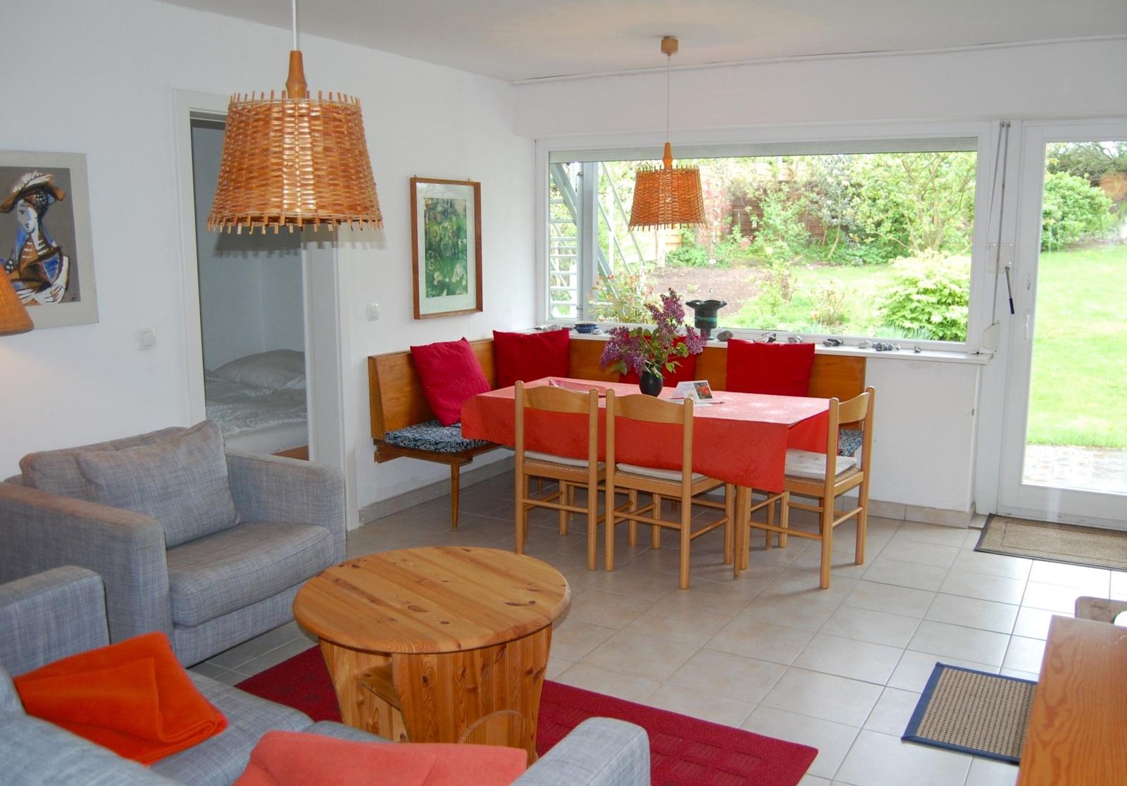 Wohn- und Essbereich mit Holztisch, Sofa und Blick auf den Garten.