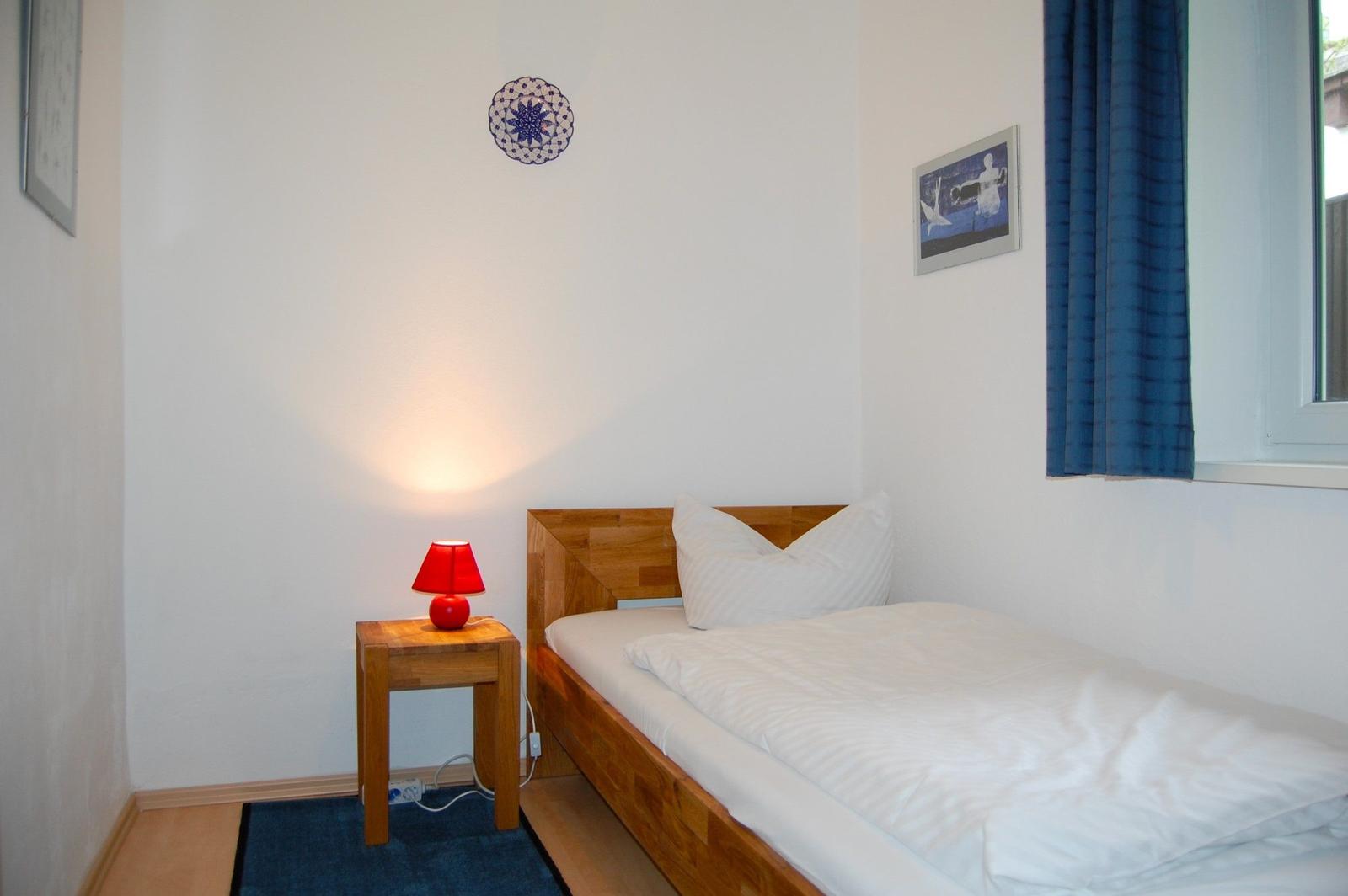 Ein Schlafzimmer mit Holzbett, Nachttisch und roter Lampe.