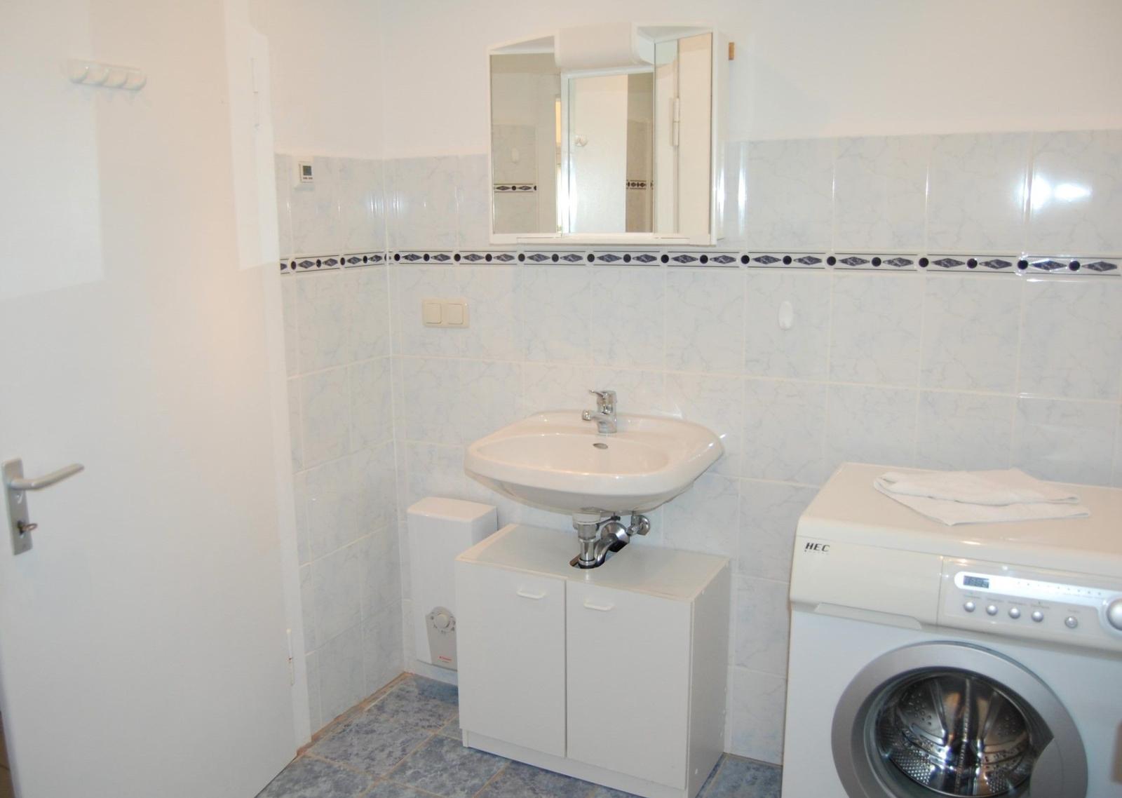 Badezimmer mit Waschmaschine und Spiegel über Waschbecken.