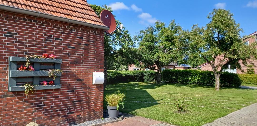 Rotes Backsteinhaus mit Garten, Blumenkasten und Satellitenschüssel.