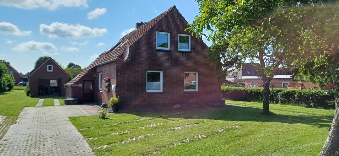 Rotes Backsteingebäude mit Garten und Terrasse unter blauem Himmel.