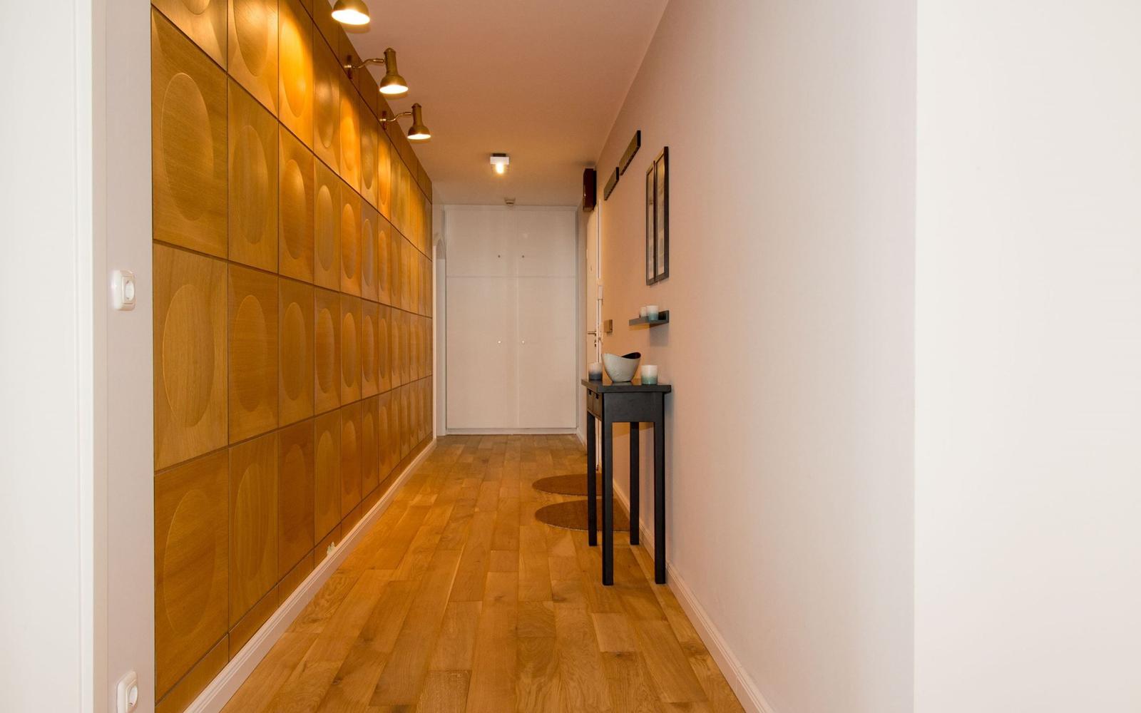 Flur mit Holzwand und Boden, Tisch und Wandregal.