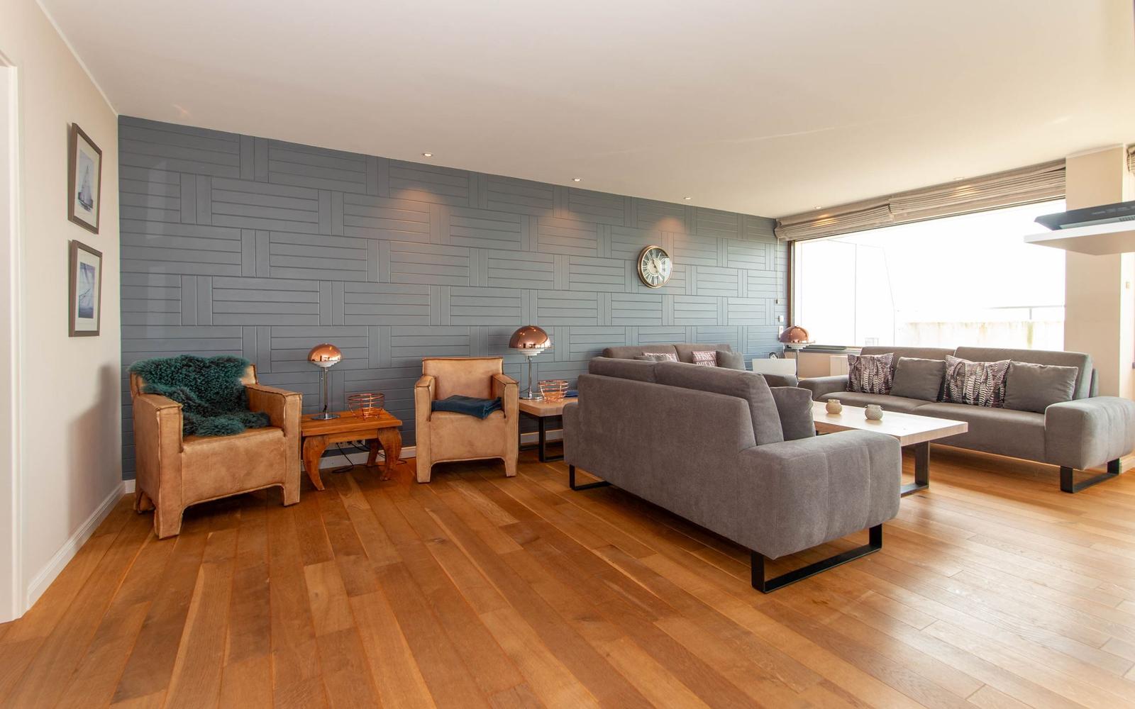 Wohnzimmer mit grauem Sofa, Holzboden und dekorativer Wand