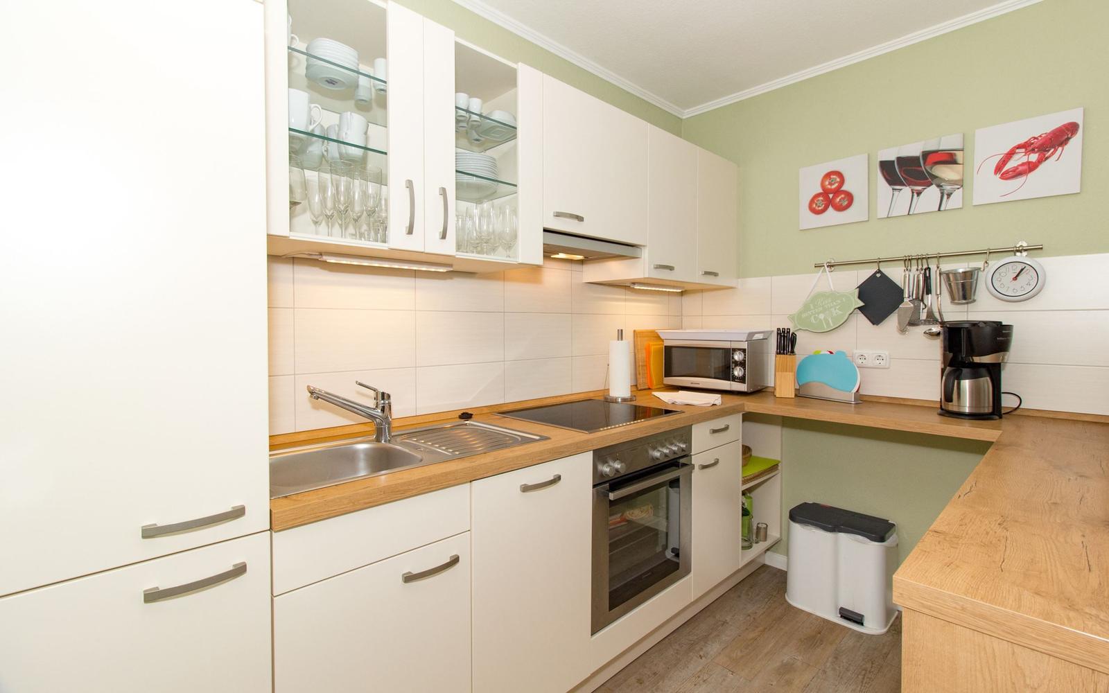 Küche mit weißen Schränken, Holz Arbeitsplatte und integriertem Herd.