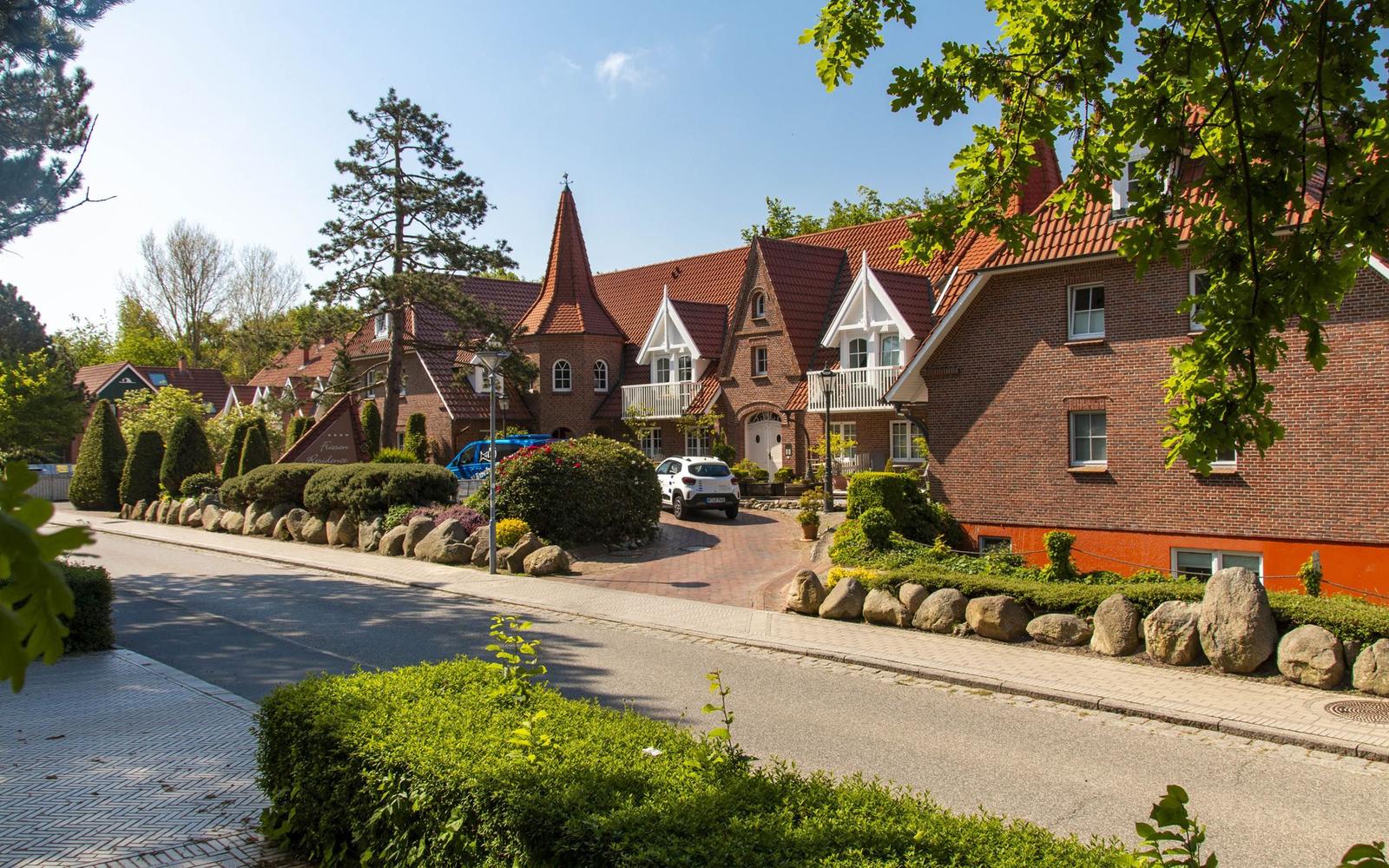 Rotes Ziegelhaus mit Dachgauben und gepflegtem Gartenbereich.
