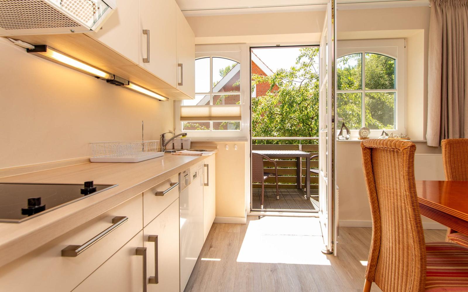 Küche mit Essbereich und Balkon. Tisch und Stühle sind aus Rattan.