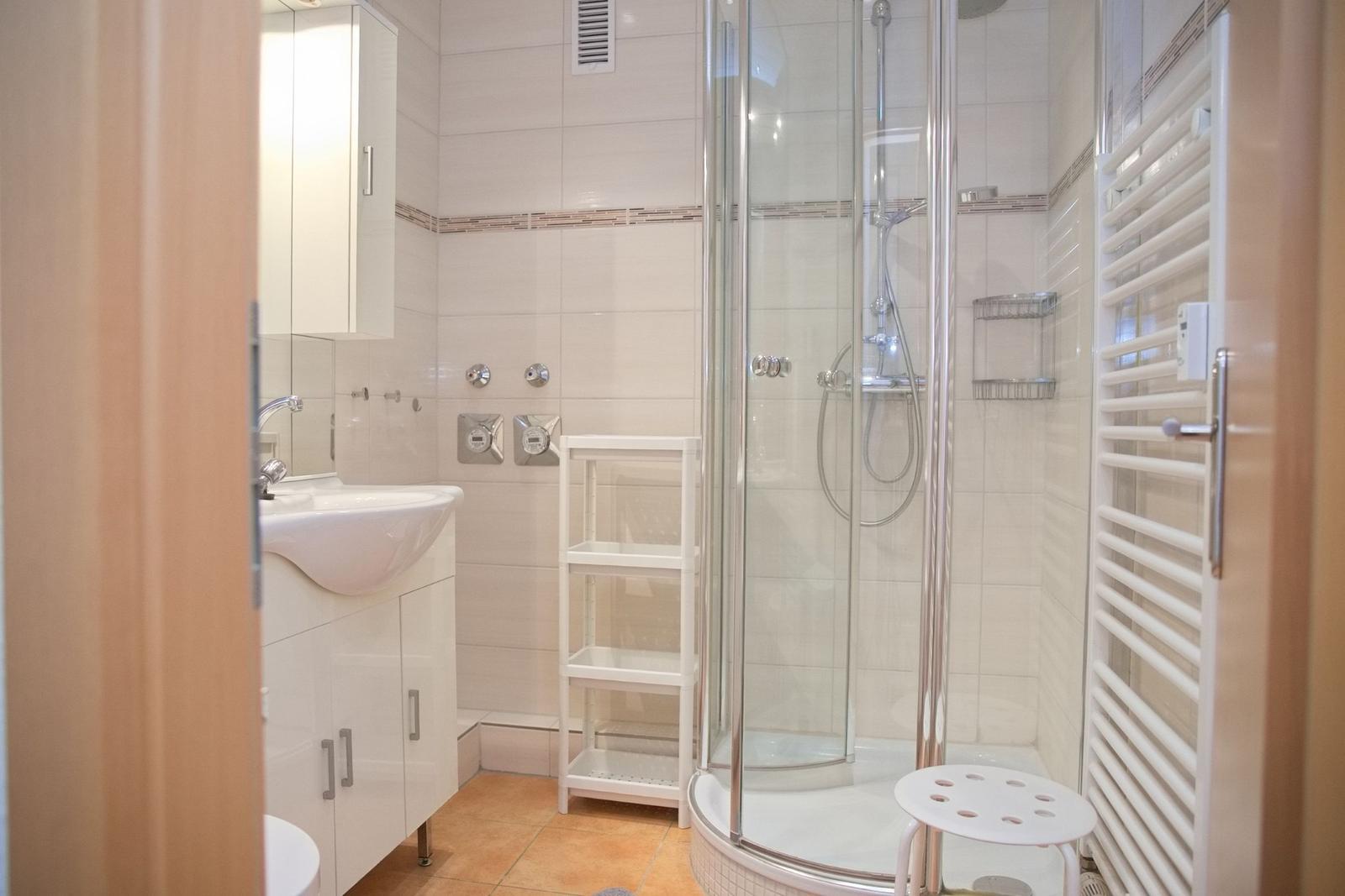 Badezimmer mit Dusche, Waschbecken und Heizung.