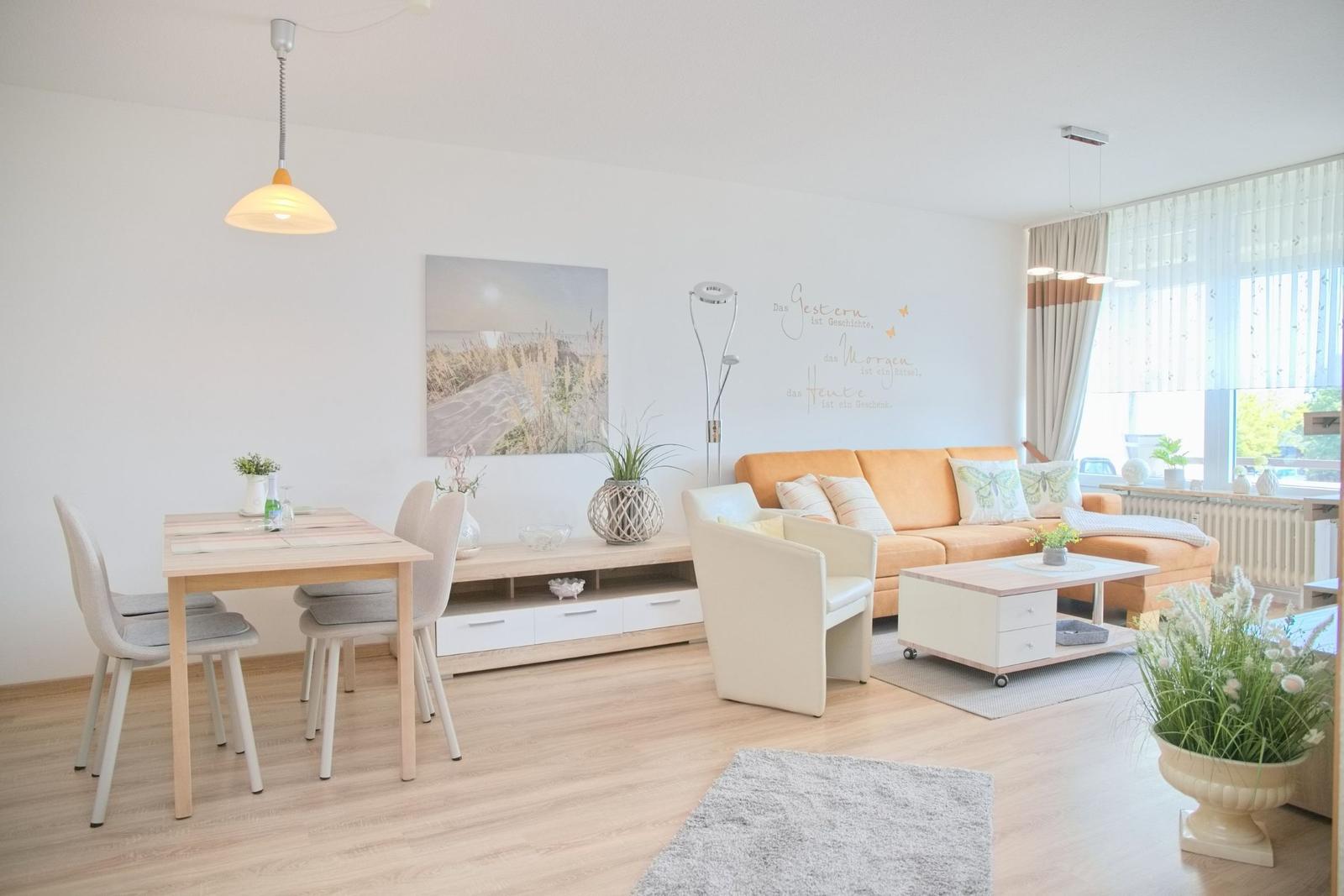 Wohn- und Essbereich mit Sofa, Tisch und Stühlen sowie Pflanzen.