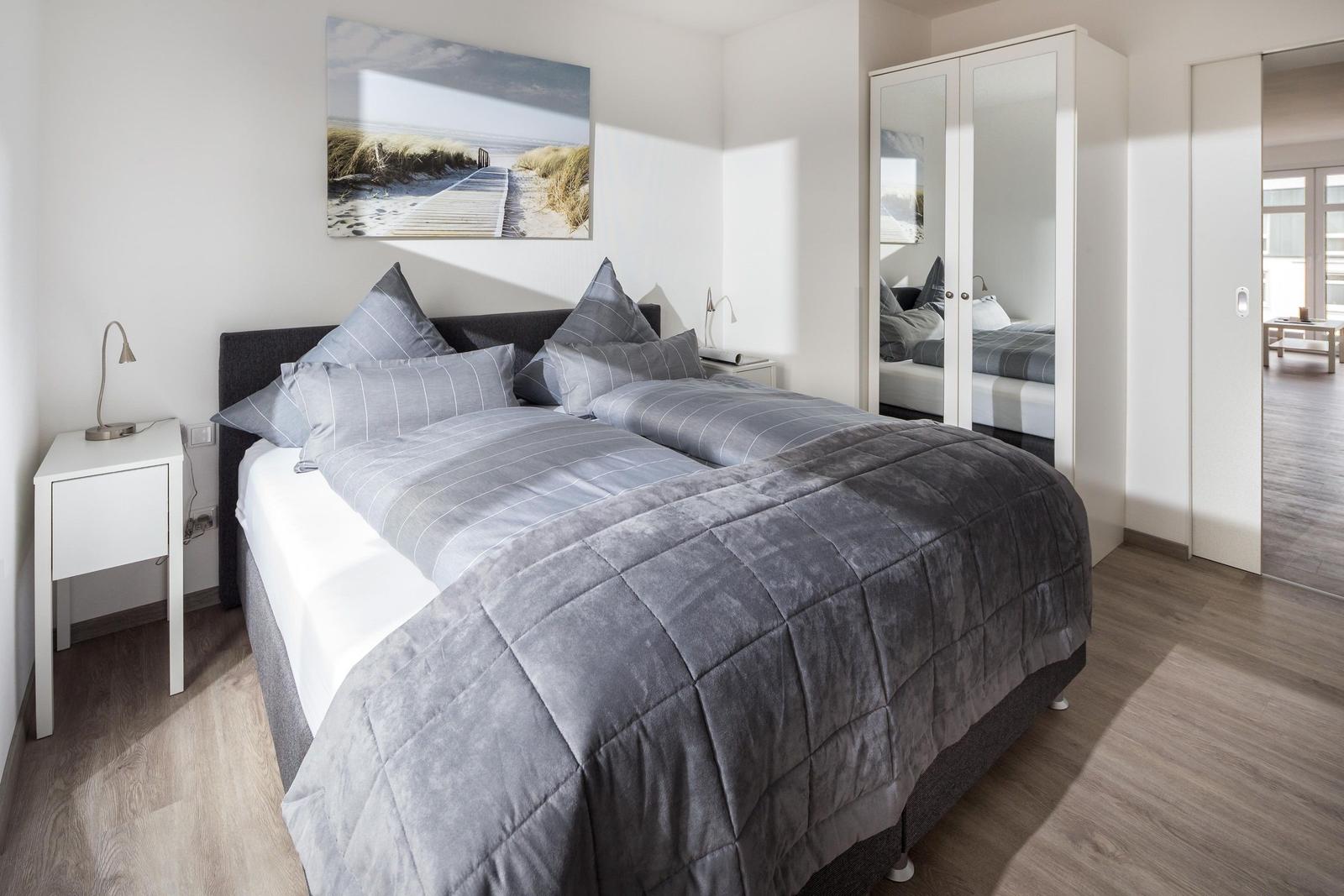 Schlafzimmer mit Doppelbett, Kleiderschrank und Wandbild.