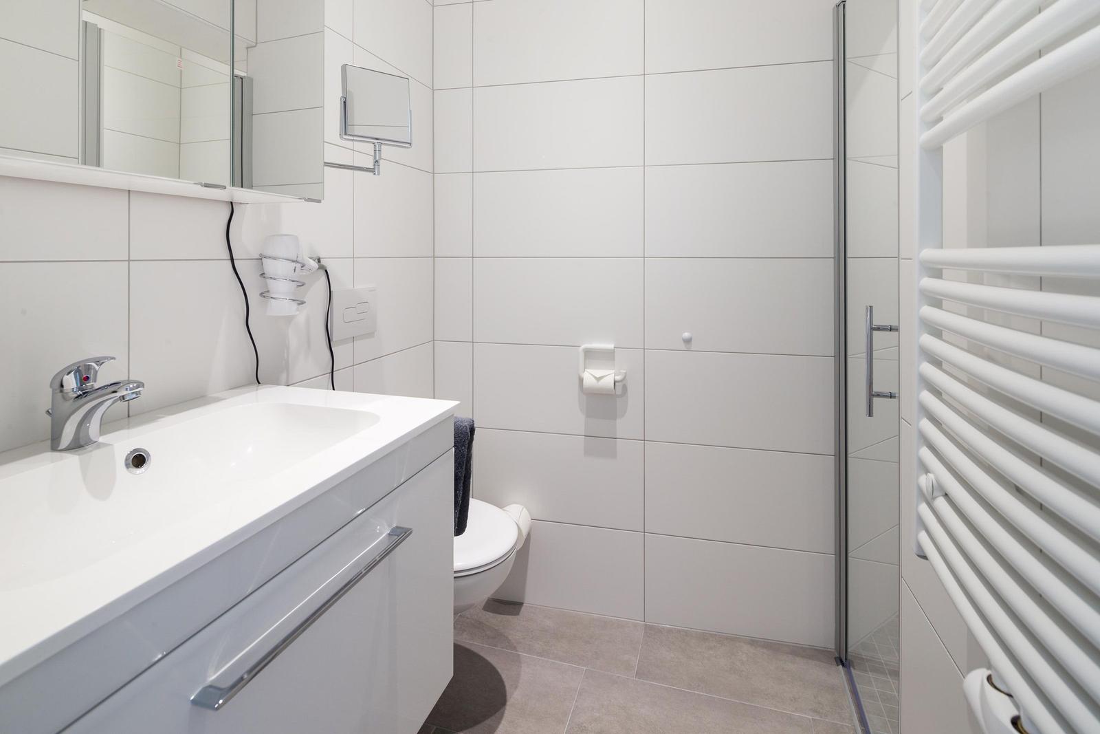 Badezimmer mit Dusche, Waschbecken und Toilette.