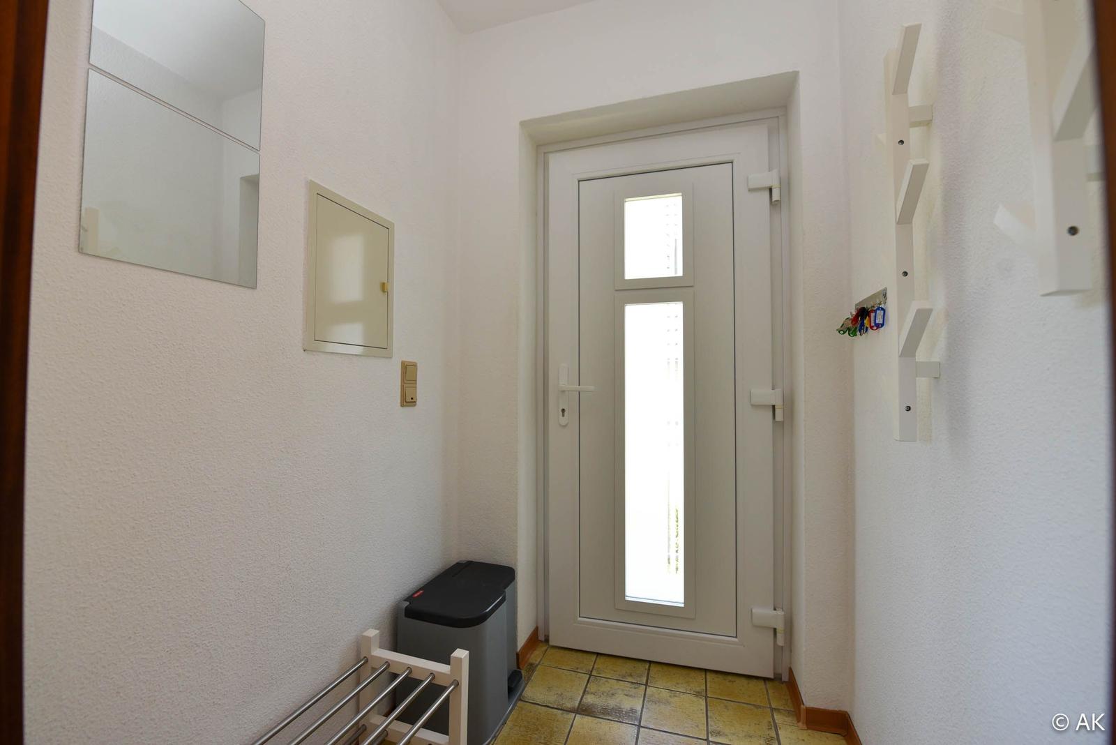 Eingangsbereich mit Tür, Spiegel, Schalter und Schlüsselhalter an der Wand.