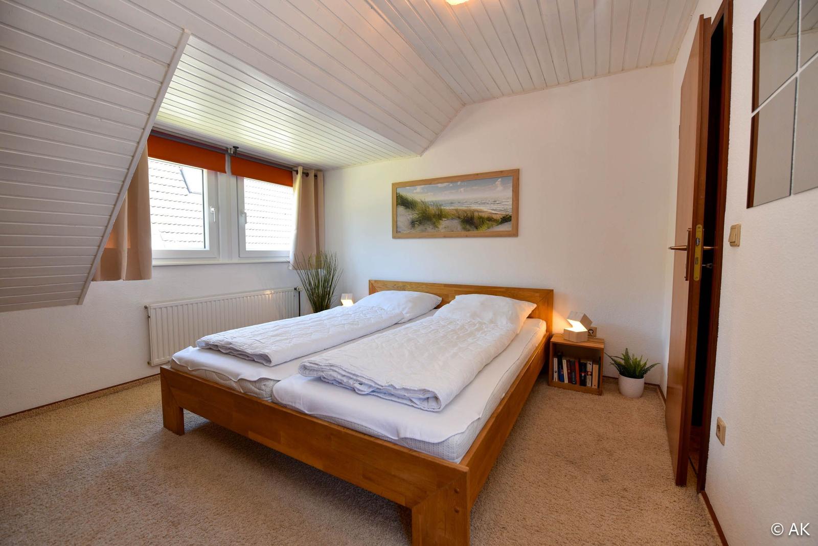 Schlafzimmer mit Doppelbett, Fenster und Holzbett.