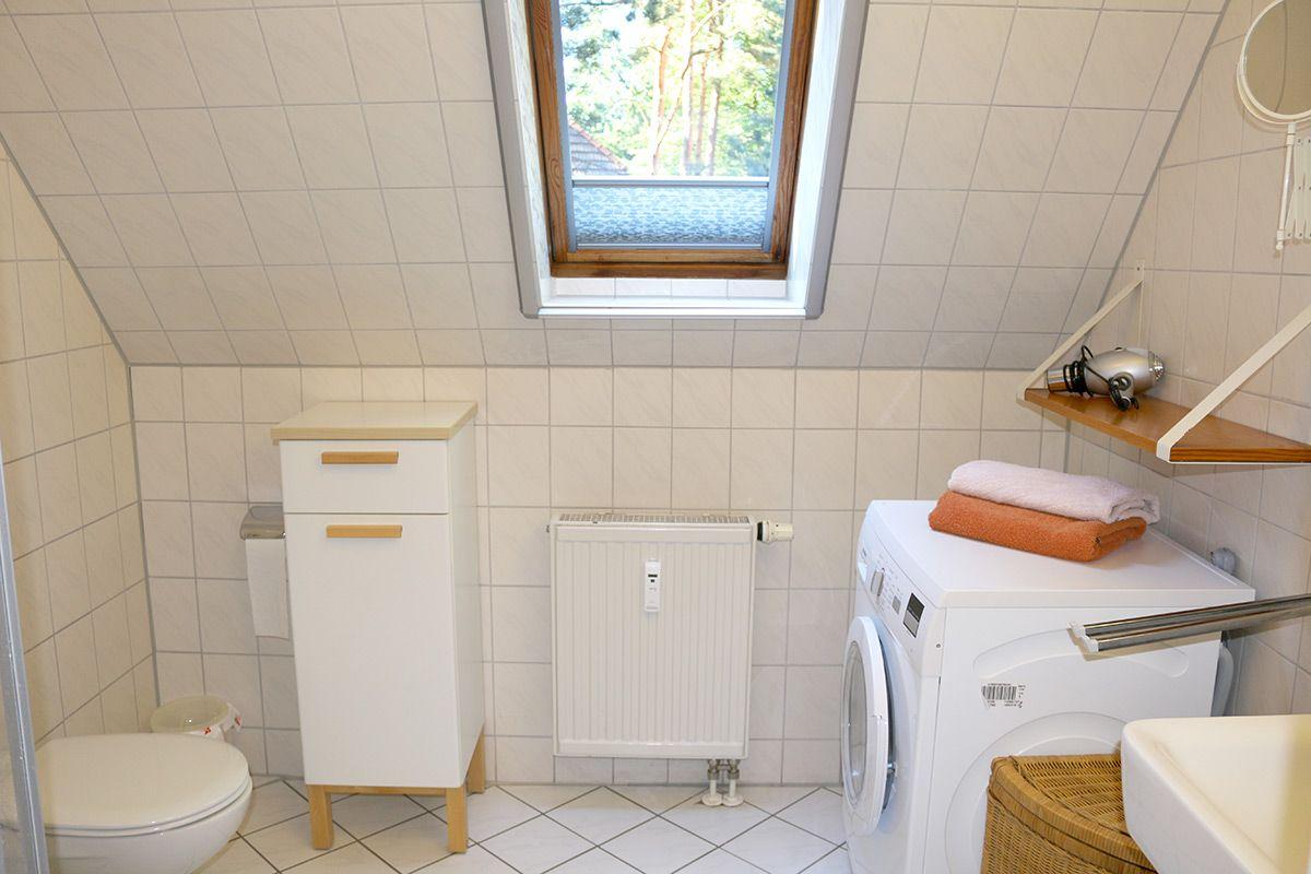 Badezimmer mit Waschmaschine, Toilette und Dachfenster.